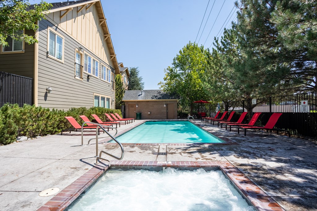 A hot tub sits in the middle of a pool surrounded by red chairs.