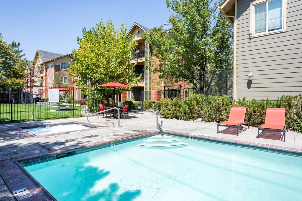 A swimming pool surrounded by a fence and chairs.