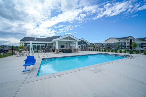 A swimming pool with a blue lounge chair and a building in the background.