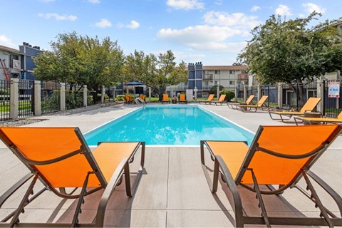 A pool surrounded by orange chairs.