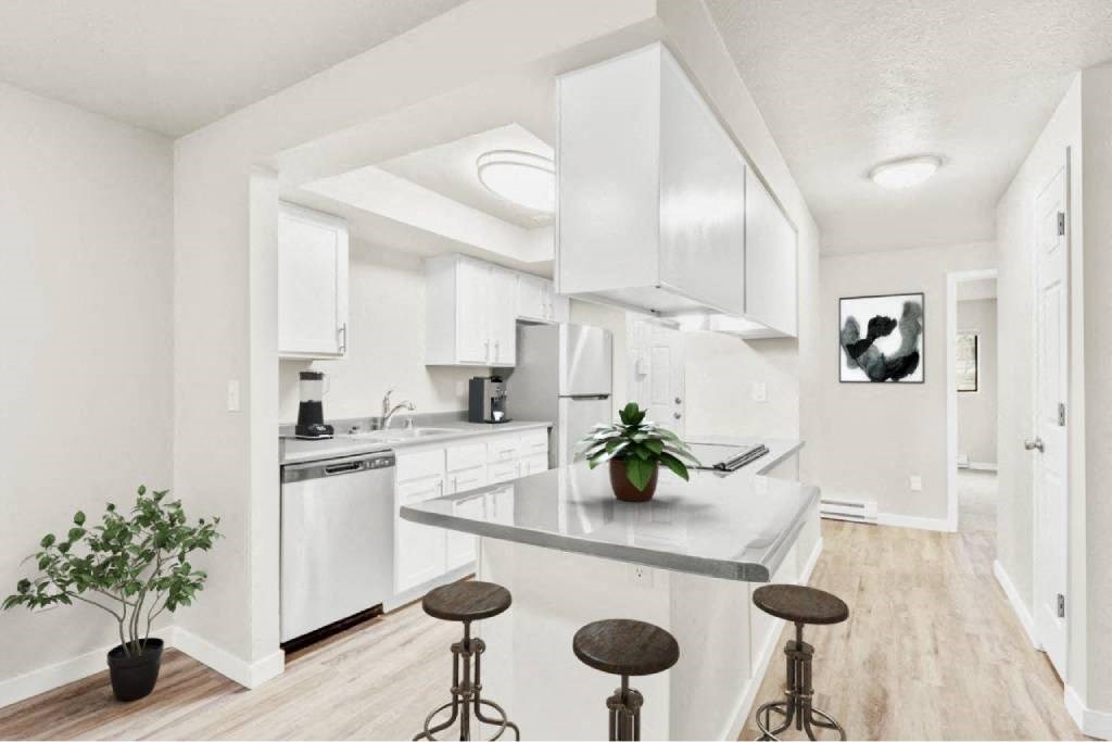 A kitchen with white cabinets and a white countertop with a potted plant on it.