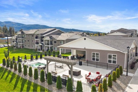 A large house with a pool and a mountain in the background at Woodland Meadows Apartments, Post Falls, ID