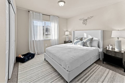 A bedroom with a large bed and a window with curtains.