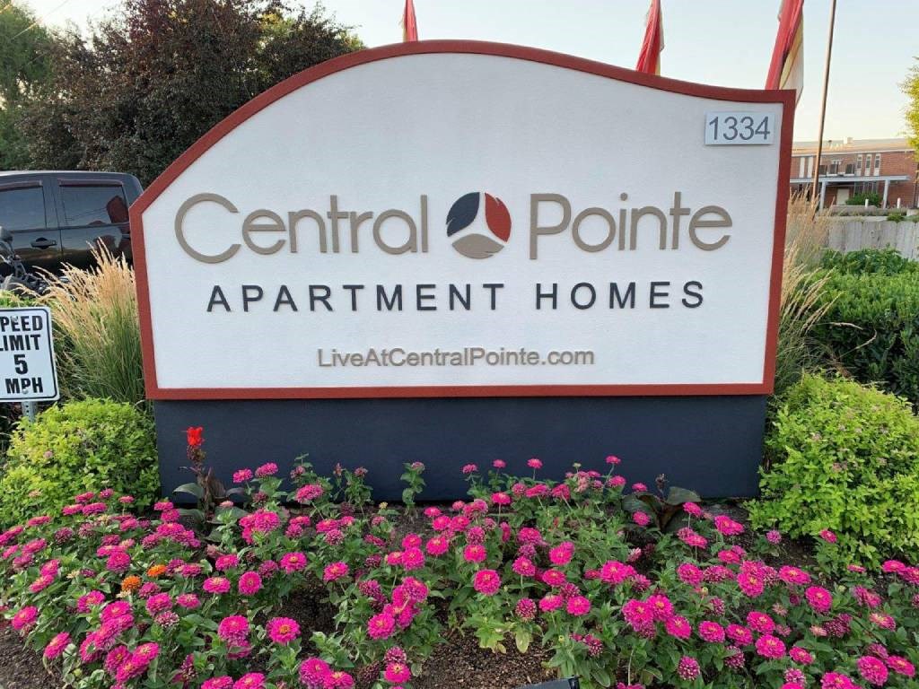 A sign for Central Pointe Apartment Homes is surrounded by flowers.
