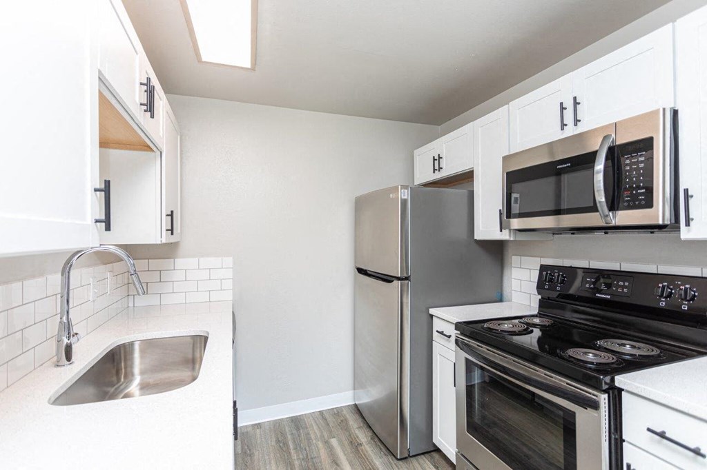 A kitchen with a stove, refrigerator, and microwave.