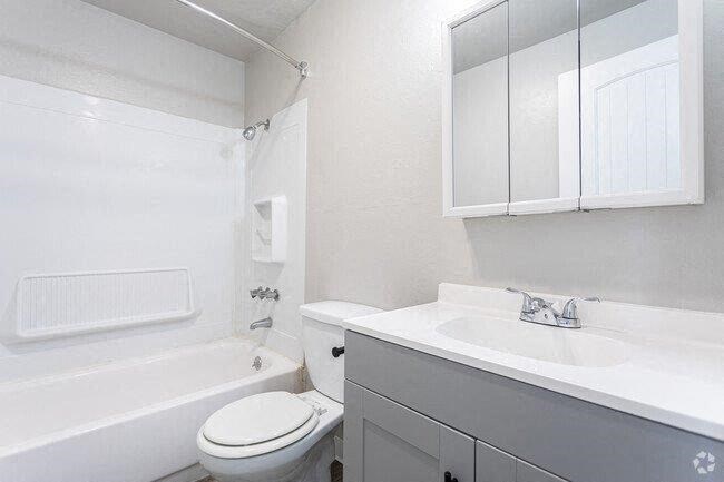 A white bathroom with a toilet, sink, and bathtub.