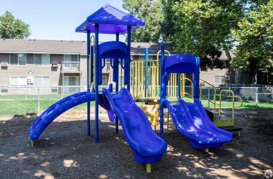 A playground with a blue slide and a yellow slide.