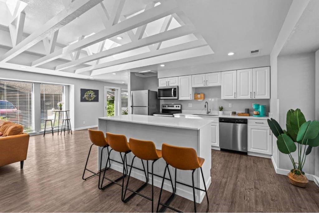 A modern kitchen with white cabinets and a large island with four chairs.