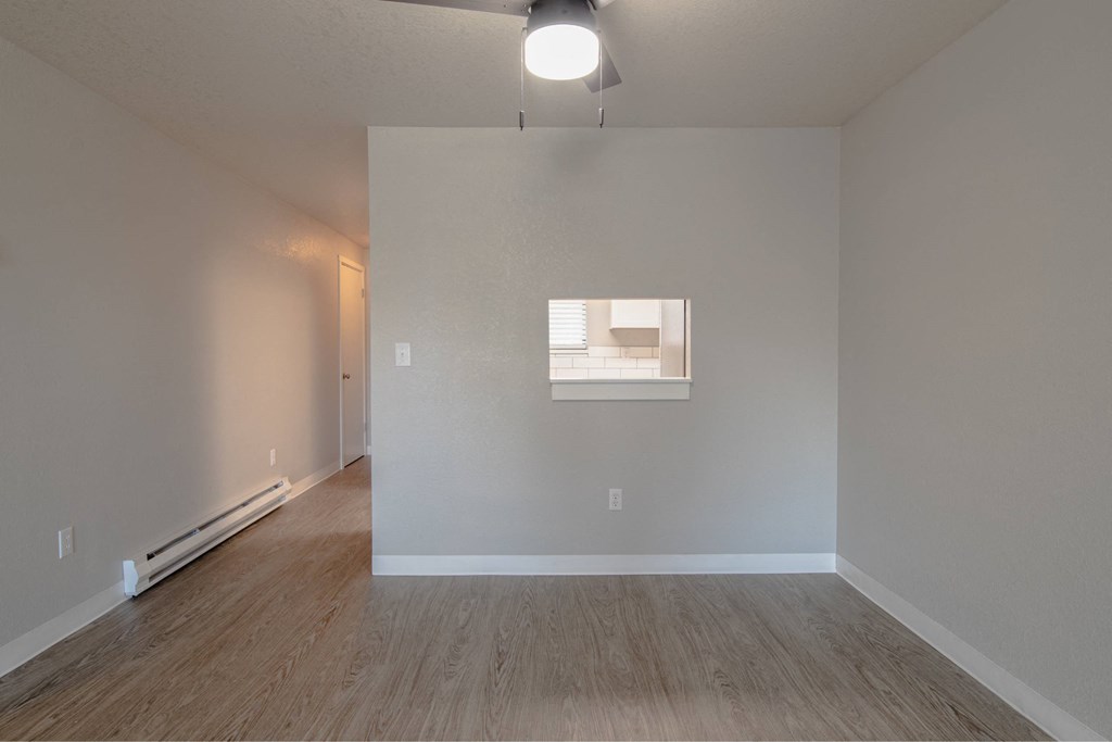 A room with a window and a wooden floor.