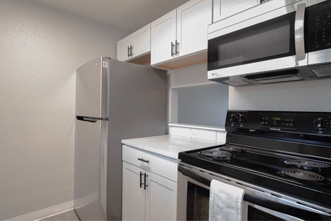 A kitchen with white cabinets and a black stove top oven.