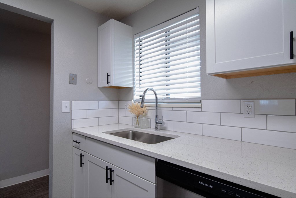A kitchen with white cabinets and a black dishwasher.