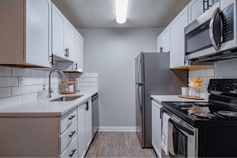 A kitchen with white cabinets and black appliances.