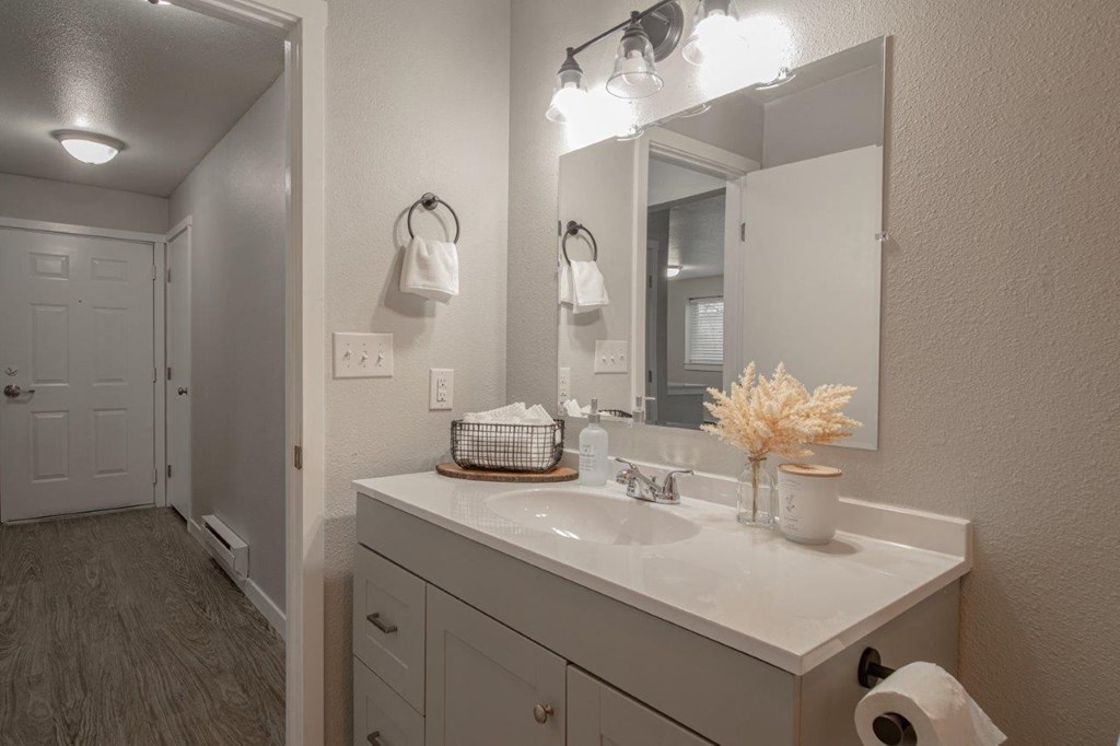 A bathroom with a white counter top and a white sink.
