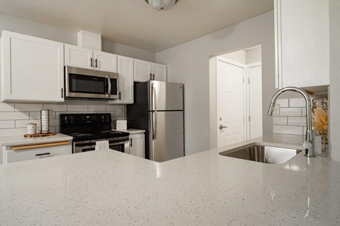 A kitchen with white cabinets and a granite countertop.