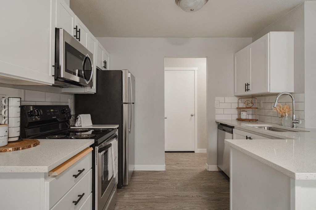 A kitchen with white cabinets and a black refrigerator.