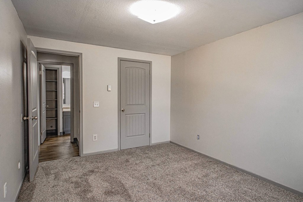A room with a carpeted floor and a door on the right.