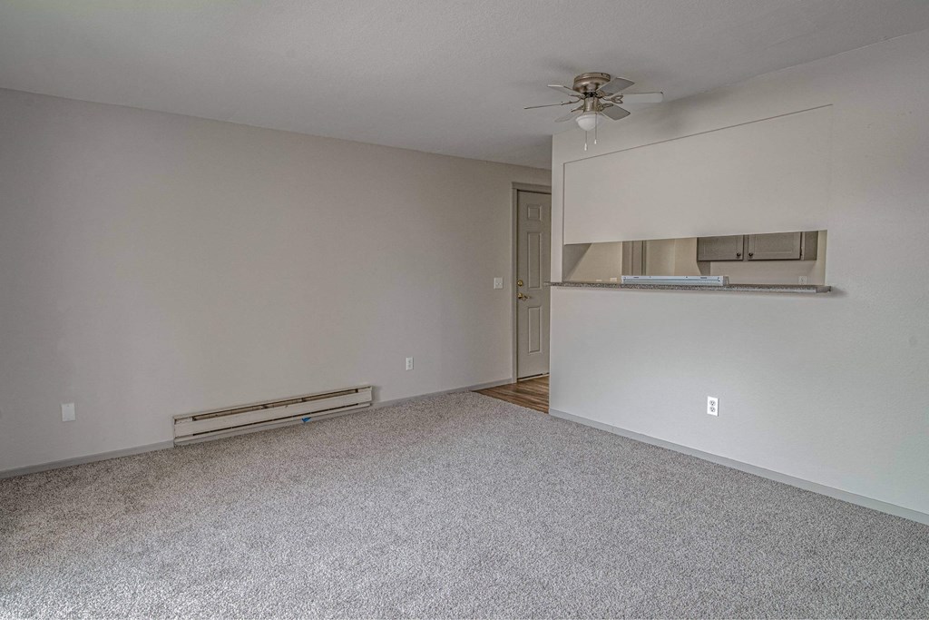 Empty room with a ceiling fan and a radiator on the wall.