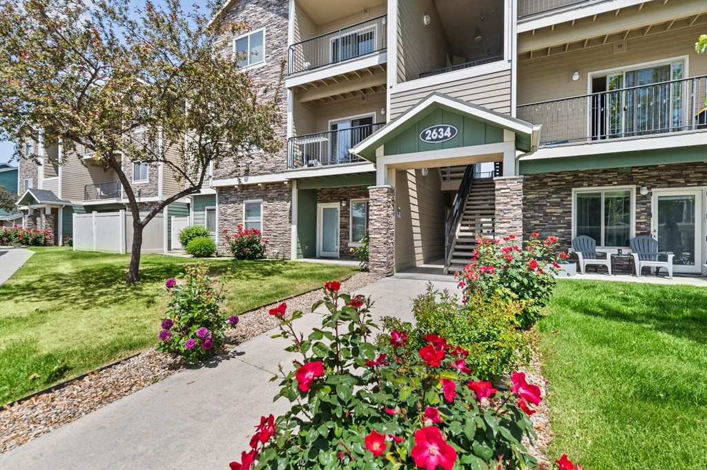 Apartment building with red flowers in front.