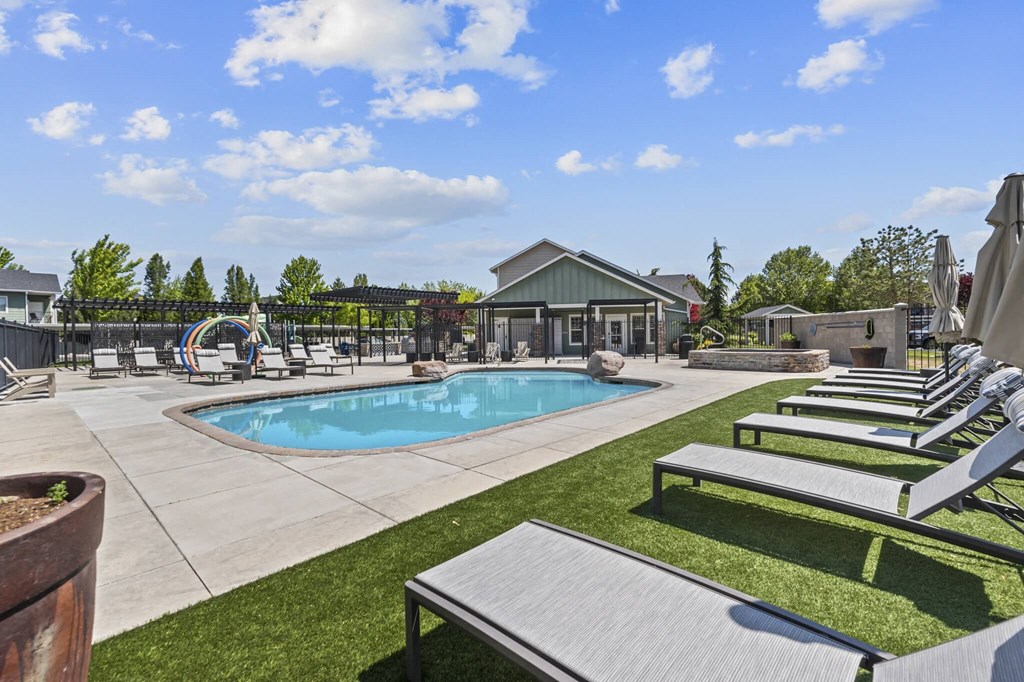 A pool area with sun loungers and a building in the background.