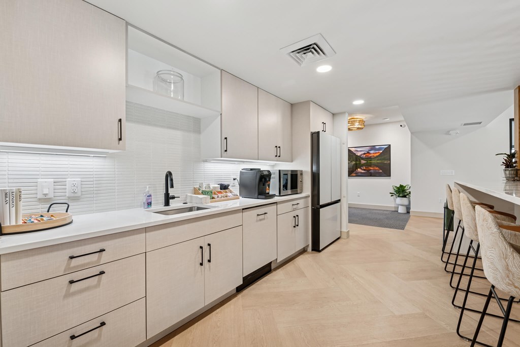 A kitchen with white cabinets and a black fridge.
