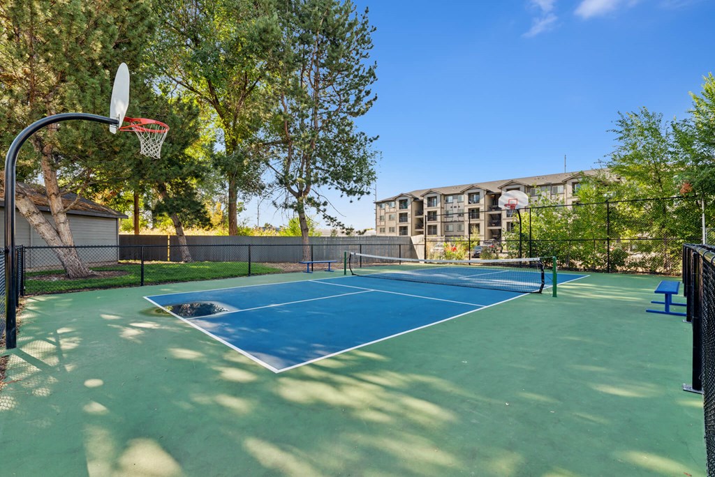 A basketball court with a blue surface and a green court in the middle.