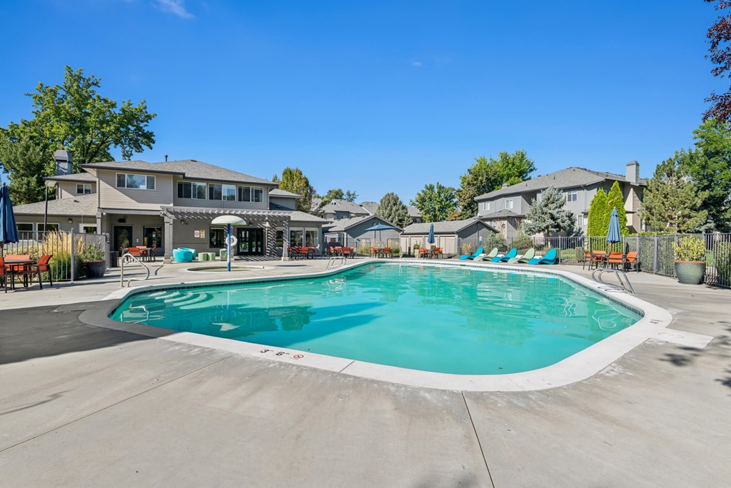 A large outdoor swimming pool surrounded by lounge chairs and umbrellas.
