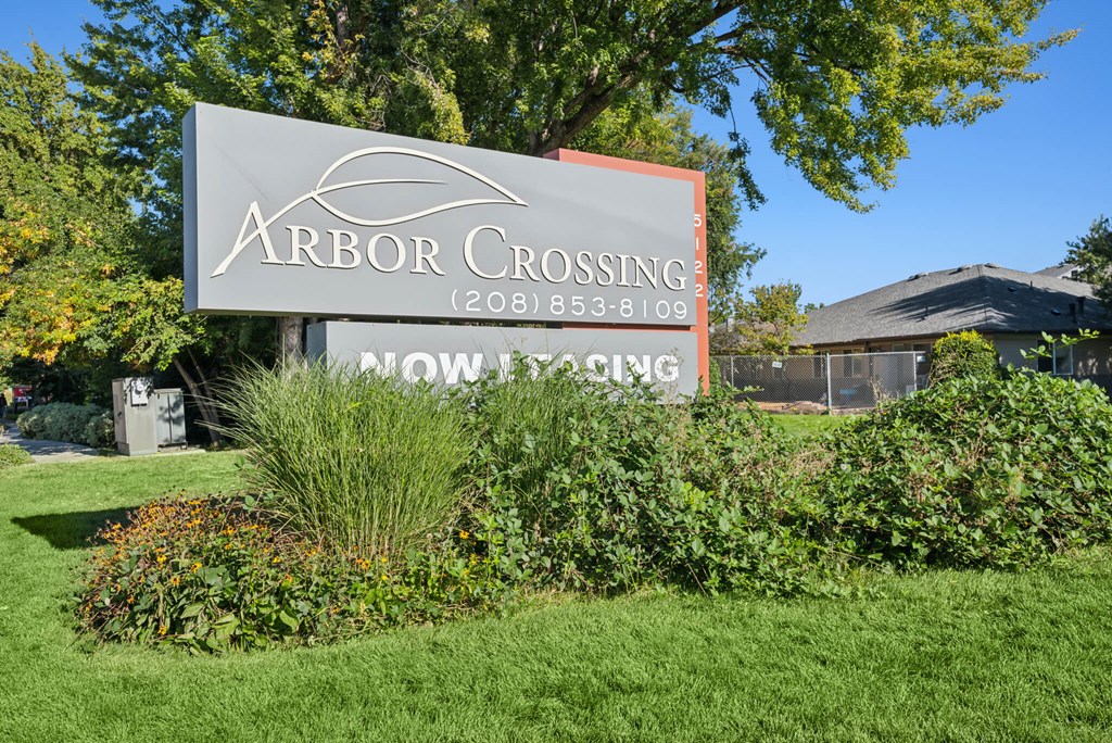 A sign for Arbor Crossing subdivision is displayed in front of a house.