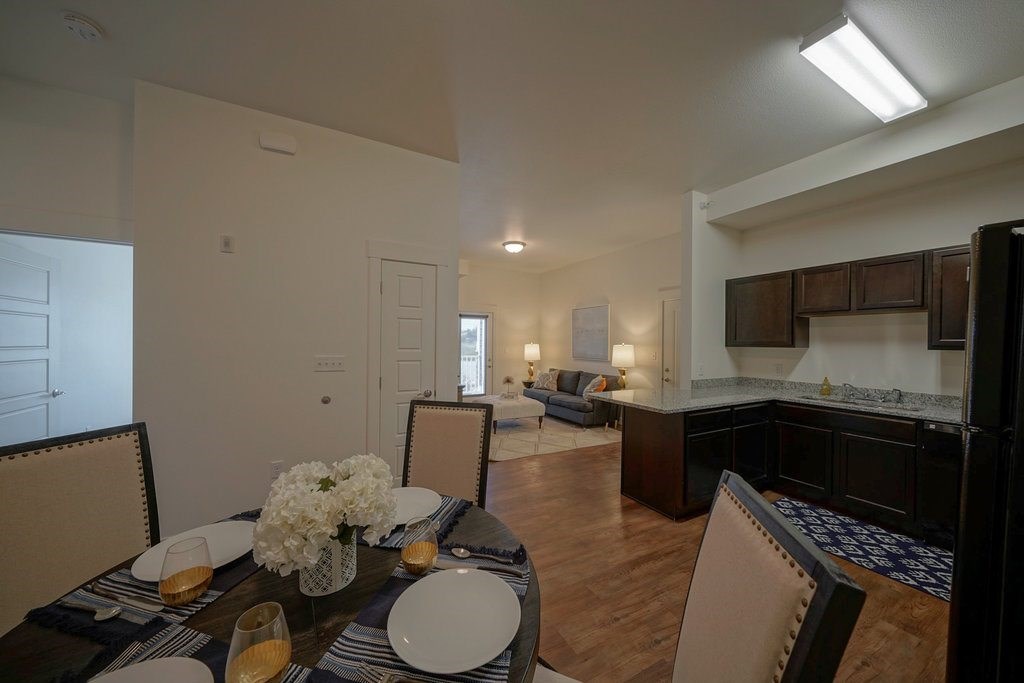 A dining room with a table set for two with candles and flowers.