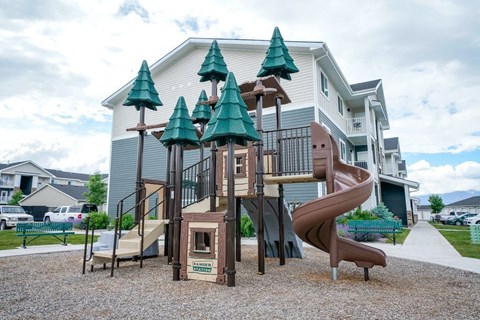 A playground with a slide and a tree-shaped structure.