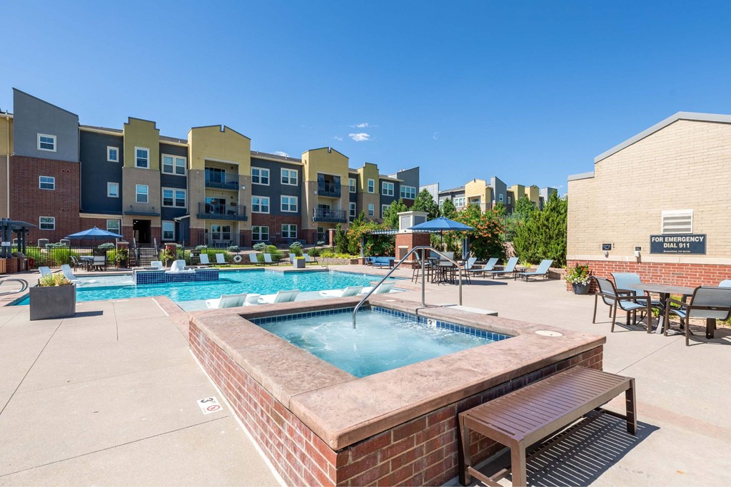 A pool surrounded by a brick wall and a bench.