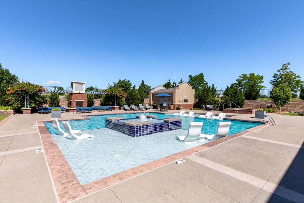 A large outdoor swimming pool with a slide and lounging chairs.