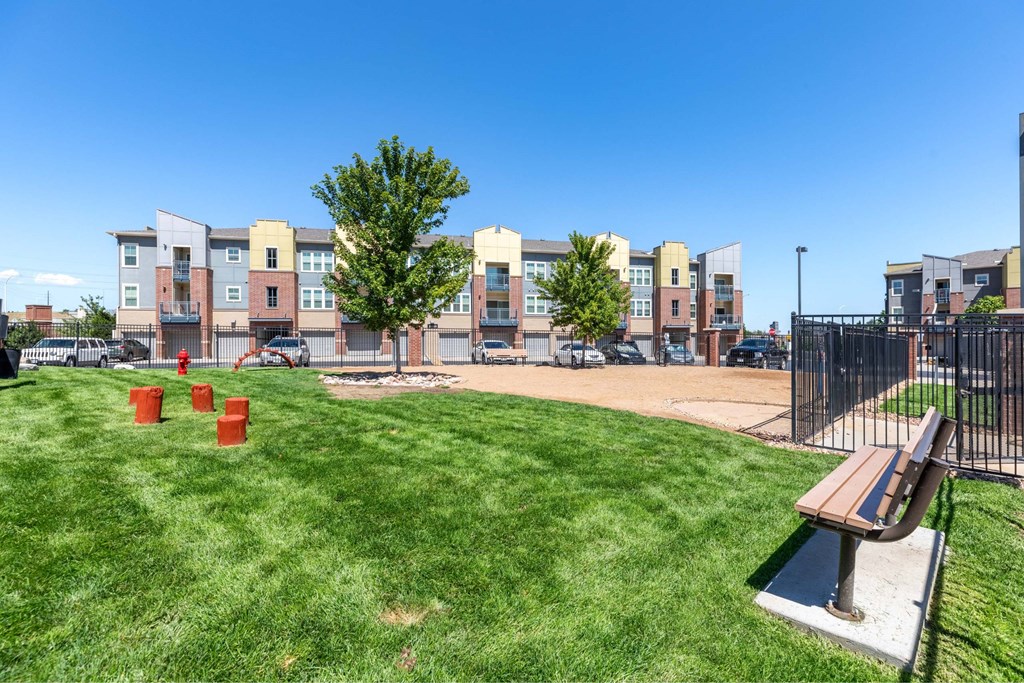 A park with a bench and a tree in front of apartment buildings.