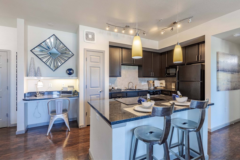 A modern kitchen with a bar area and a dining table set for two.