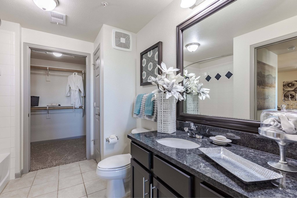 A bathroom with a toilet, sink, and mirror.