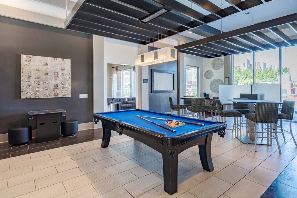 A pool table in a room with a brown wall and a painting.