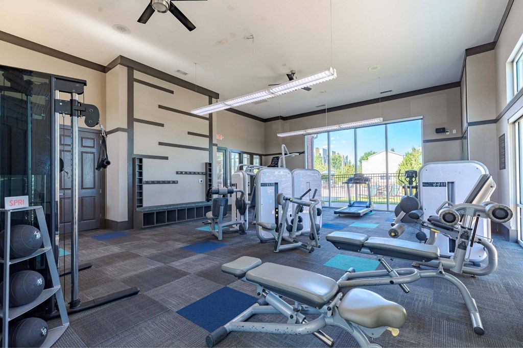 A gym with a variety of equipment including a leg press machine, a rowing machine, and a bench press.