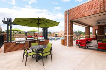 A patio with a table and chairs under a green umbrella.