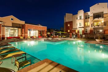 A swimming pool with lounge chairs and a building in the background.