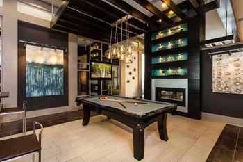 A pool table in a room with a fireplace and a painting on the wall.