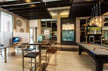 A billiard table is in the middle of a room with a bar and a television.