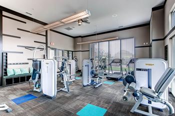 A gym with a variety of equipment including a treadmill, weights, and a bench press.