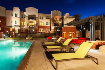 A pool area with lounge chairs and a building in the background.