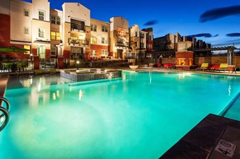A swimming pool in front of apartment buildings at dusk.