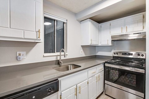 A modern kitchen with white cabinets and stainless steel appliances.