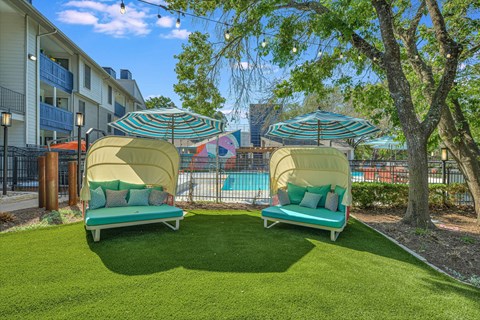 Canopy daybeds with striped umbrellas on artificial turf at Peaks @ NW Hills Apartments, Texas, 78731
