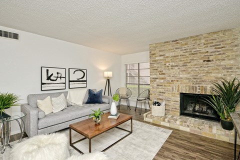 A living room with a grey couch, a wooden coffee table, a fireplace, and a rug.