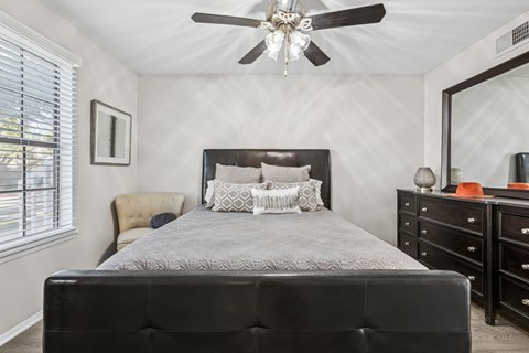 Bedroom with dark wood furniture and ceiling fan at Polo Club Apartments, Austin
