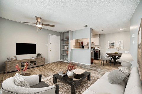 A living room with a white couch, a black coffee table, and a flat screen TV.