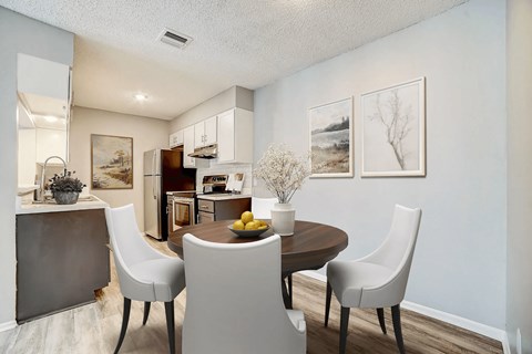 A dining room with a table set for two and a kitchen area in the background.