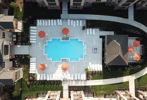 A swimming pool surrounded by orange umbrellas and white lounge chairs.